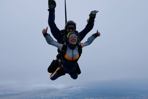 Çift kişilik paraşütle atlama. Bir kız ve eğitmeni bulutlu gökyüzünde uçuyorlar.. - Fotoğraf, Görsel