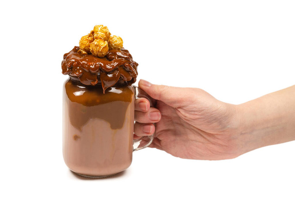 Шоколадний молочний коктейль зі збитими вершками, печивом, вафельками, подається в скляній мулярній банці. "У жіночій руці ізольовано. Простір для тексту або дизайну
. - Фото, зображення