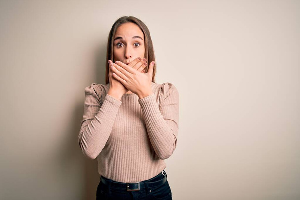 Young beautiful woman wearing casual sweater standing over isolated white background shocked covering mouth with hands for mistake. Secret concept. - Valokuva, kuva