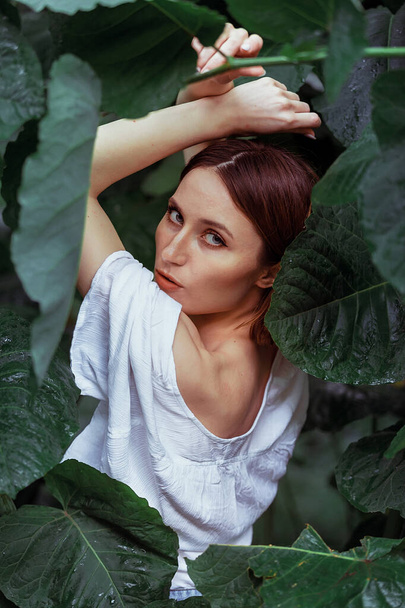Woman in green leaves enjoying nature. Portrait of young beautiful woman with healthy glow smooth skin with natural green palm leaf - Foto, Imagem