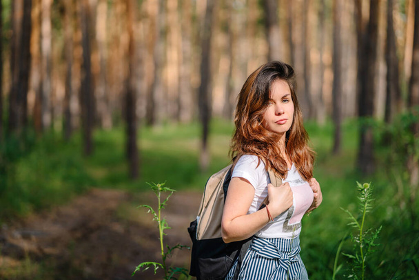 松林の中にバックパック付きの若い女の子として観光のテーマ。テキストコピースペースのハイキングスタイルと場所 - 写真・画像
