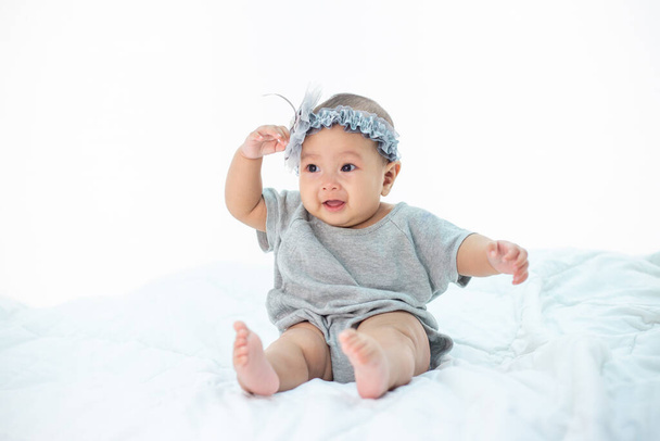 Happy baby sitting on a white bed - Photo, Image