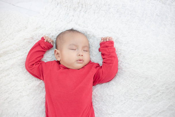 Babies wearing red shirts sleeping in bed - Foto, afbeelding