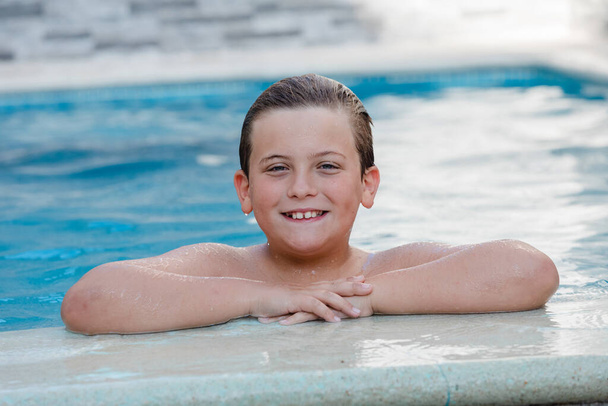 Beautiful blond child in the swimming pool on the summer  - Foto, Bild