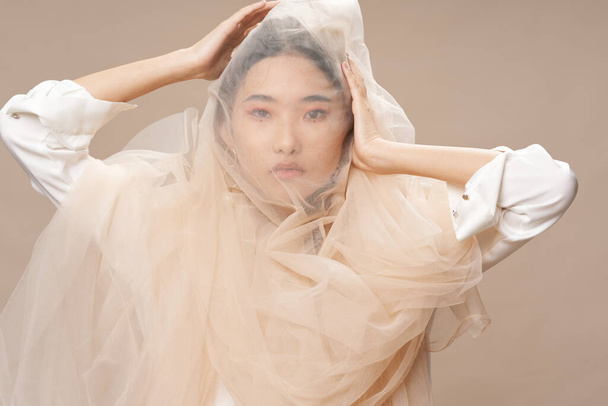 Hübsche Frau asiatischen Aussehens mit einem transparenten Tuch auf dem Kopf  - Foto, Bild