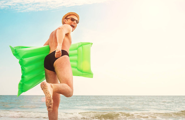 Man in straw hat runs with air swimimg mattress in the sea - Zdjęcie, obraz