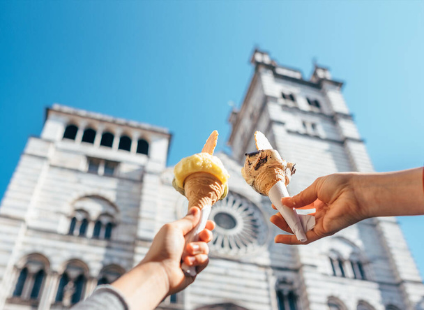 Két kézzel vesz fagylaltot a San Lorenco katedrális közelében.  - Fotó, kép