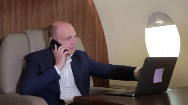 Lähikuva nuori liikemies työskentelee tietokone puhuu puhelimessa Flying omassa Personal Plane Business Jet - Materiaali, video