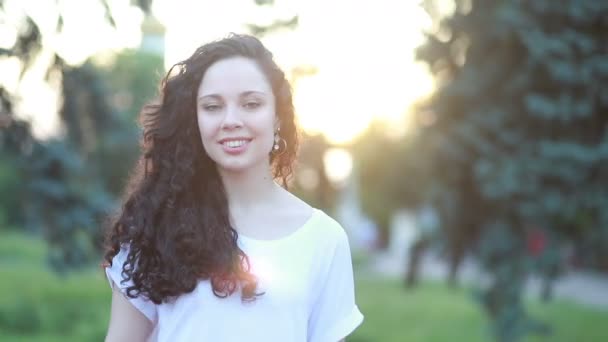Sunshine young smiling woman with curly hair look at camera smile walking in the park portrait happy slow motion summer face sunset beautiful lady outdoor closeup cute - Video