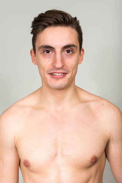 Studio shot of young handsome muscular man with brown hair shirtless against white background - 写真・画像
