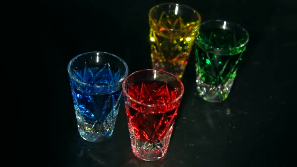 Sterke alcohol. Een klein borrelglaasje met veelkleurige alcoholische cocktails. Mooie schaduwen op donkere achtergrond - Video