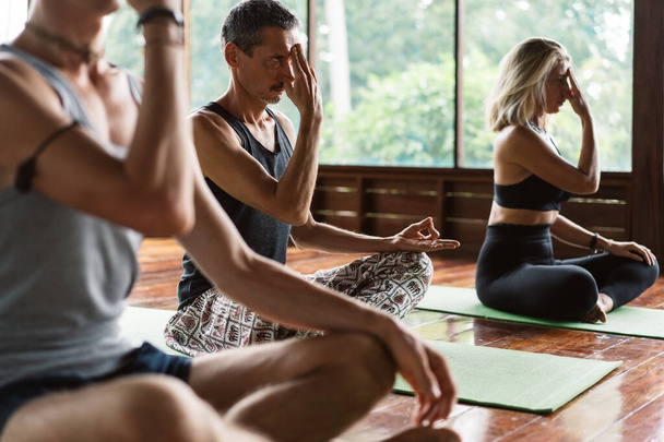 Un grupo de personas que asisten a una clase de yoga en un entorno tropical de un retiro de yoga / meditación
 - Foto, Imagen