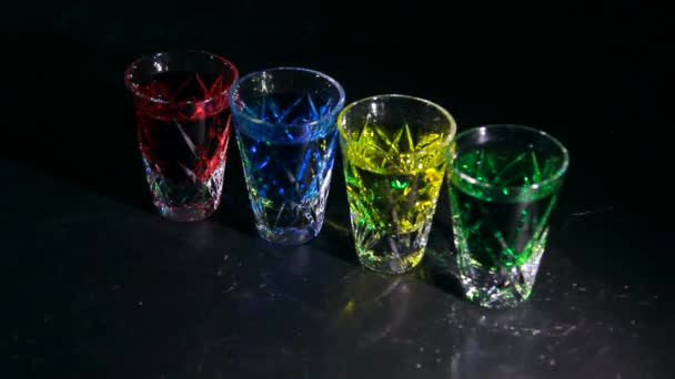 Silný alkohol. Malé skleničky s pestrobarevnými alkoholickými koktejly. Krásné stíny na tmavém pozadí - Záběry, video