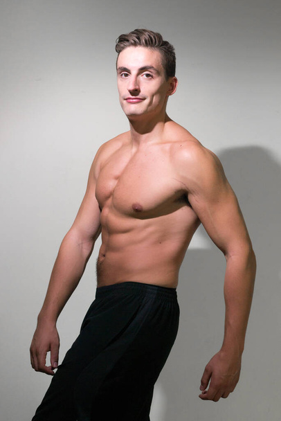 Studio shot of young handsome muscular man with brown hair shirtless against white background - Foto, afbeelding