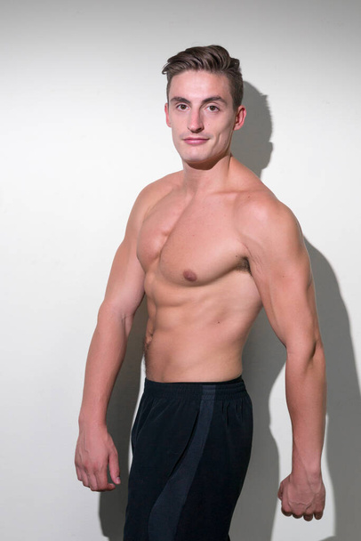 Studio shot of young handsome muscular man with brown hair shirtless against white background - Zdjęcie, obraz