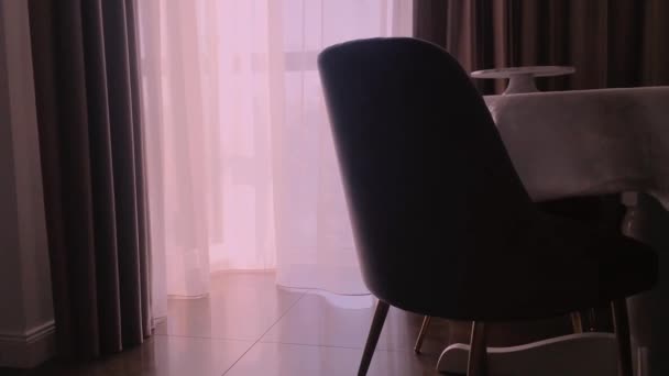 Uitzicht op een eetkamer, ronde tafel, stoelen en raam versierd met gordijnen, meubels en luxe interieur - Video