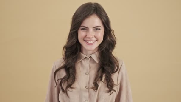 A smiling woman is doing thumb-up gesture isolated over a beige background - Imágenes, Vídeo
