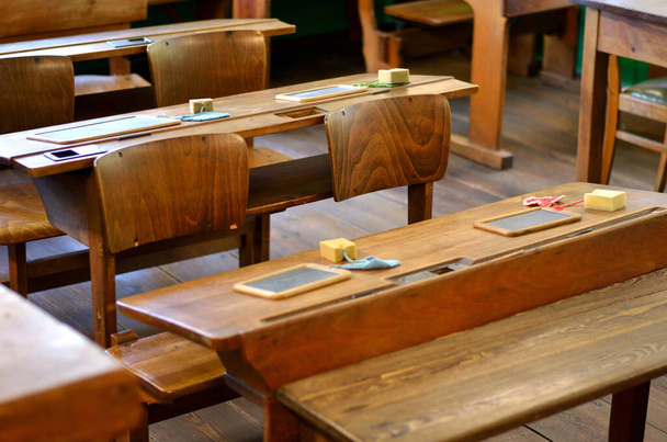 Alte Tische und Stuehle mit Schiefertafeln und Schwamm in einem alten Klassenzimmer - Foto, immagini