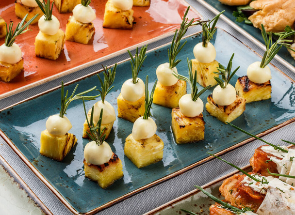 Pyszne przekąski z serem i ananasem na stole bankietowym. Żywność gastronomiczna, kanapki i przekąski - Zdjęcie, obraz