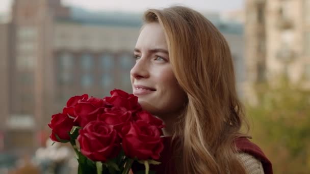 Smiling girl holding bunch outdoors. Cheerful woman smelling flowers on street. - Filmagem, Vídeo