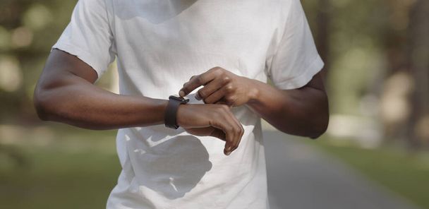 Zwarte man het controleren van zijn activiteit status op smartwatch - Foto, afbeelding