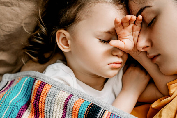 Young mother and baby of 2 years sleep together hugging, daytime sleep concept for children. Mom fell asleep with her baby while putting her to sleep - Foto, imagen