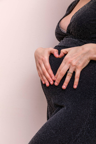 Großaufnahme des Bildes einer schwangeren Frau, die ihren Bauch mit den Händen berührt. Hochauflösendes Bild. - Foto, Bild