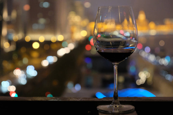 Cierra una copa con vino tinto adentro. Borrosa coloridas luces de noche urbanas de fondo. En el Bund de Shanghai China
 - Foto, Imagen