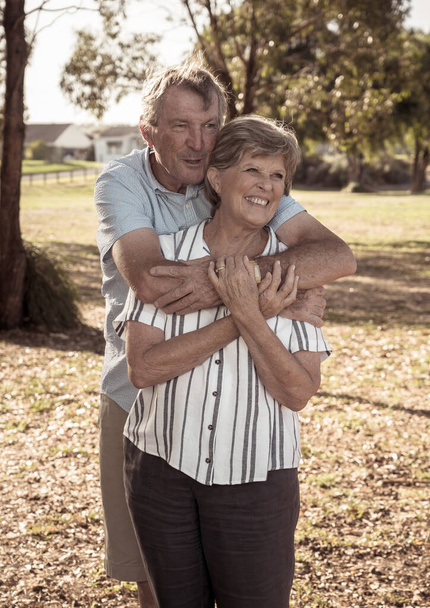 Portrait of caucasian senior couple in their 70s embracing showing love and affection in the park. Aging together, love, retirement lifestyle and back to life after coronavirus concept. - Foto, Imagem