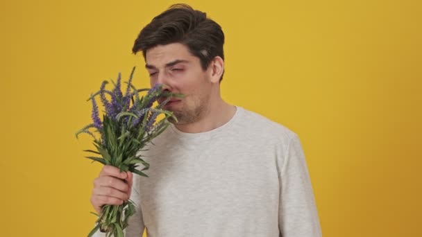 Bearded sick man sniffing the flowers and having allergy then showing pills and becoming happy over yellow background - Séquence, vidéo