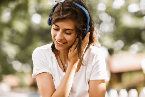 Izgalmas lány zenét hallgat fejhallgatóval az utcán a haj mozog - Fotó, kép