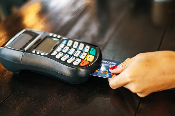 Image en gros plan d'une femme payant par carte de crédit dans un café - Photo, image