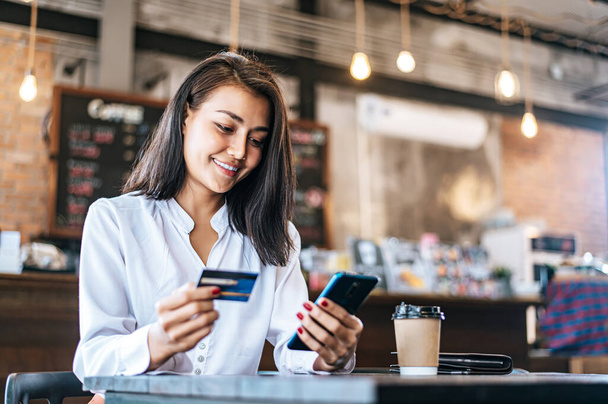 Platit zboží kreditní kartou přes smartphone v kavárně. - Fotografie, Obrázek