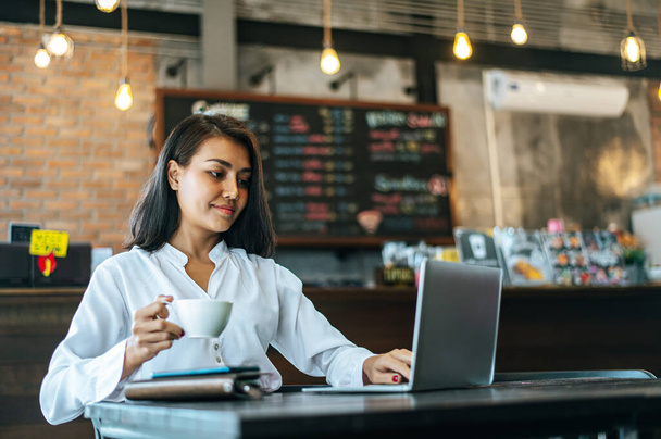 mulher sentada e trabalhando com um laptop em uma cafeteria
 - Foto, Imagem