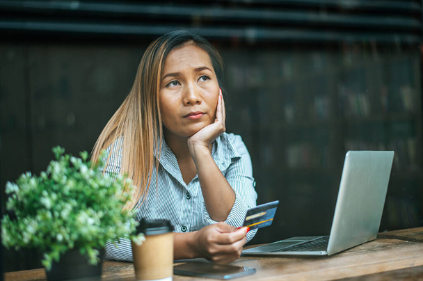 сидящая женщина, думающая о балансах кредитных карт, ноутбуке. - Фото, изображение