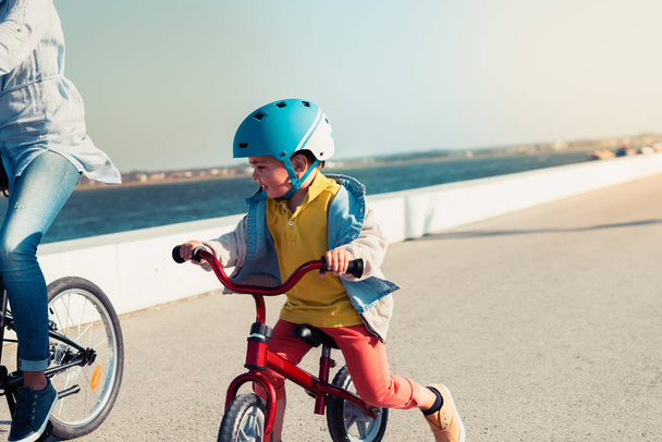 Malý kluk jezdí na kole s matkou na kole v městském parku - Fotografie, Obrázek