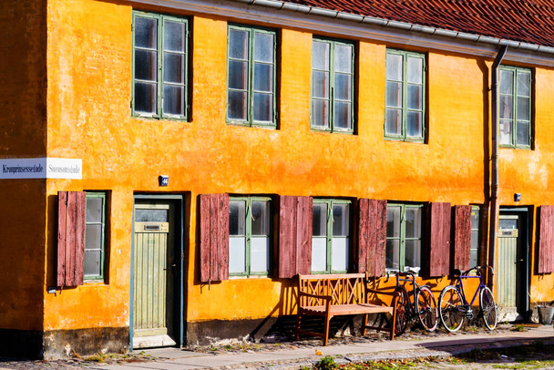 COPENHAGEN, DINAMARCA - 8 DE OCTUBRE DE 2016: Bonitas casas amarillas antiguas de Nyboder, distrito medieval de Copenhague, Dinamarca. Bicicleta retro estacionada frente al edificio sobre un pavimento
. - Foto, Imagen