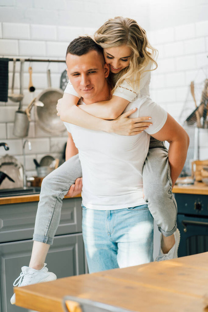 happy young lovers couple spinning and fooling around in kitchen. - Photo, image