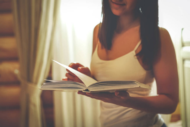 Young woman reading book at home, closeup - Valokuva, kuva