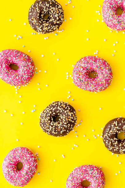 Donuts flat lay pattern on yellow background, top view - Zdjęcie, obraz