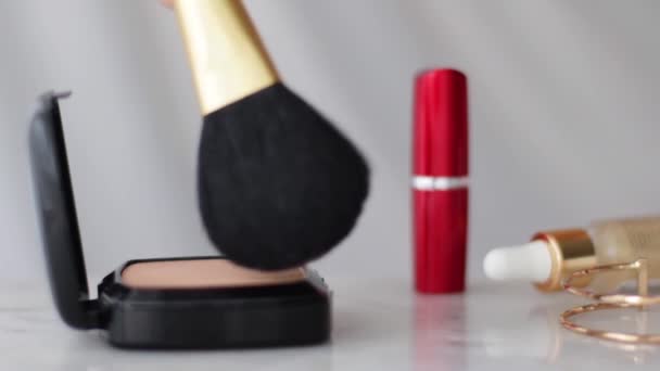 Meikkivalmisteet marmoripöydällä, jauheella, huulipunalla ja harjalla kosmetiikka- ja kauneusmerkin taustana - Materiaali, video