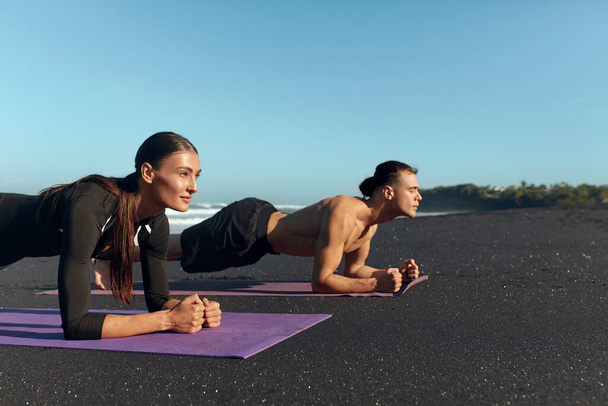 Beach. Couple Workout On Yoga Mat. Handsome Shirtless Man And Sexy Woman Doing Plank In Morning On Coast. Exercises For Strong Muscular Body On Summer Vacation. - Foto, Bild