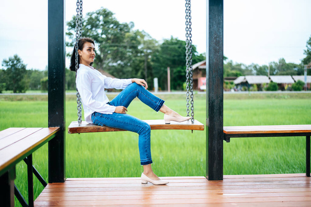 The woman sat on the swing and laid her hands on her knees - Photo, Image