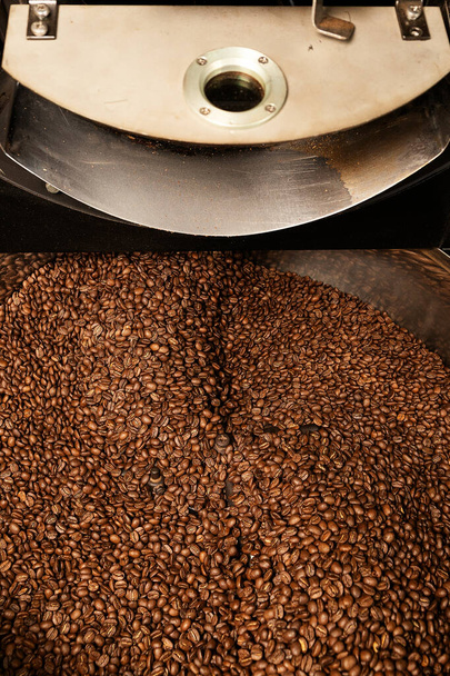 Frescos granos de café naturales tostados en cascada de la máquina de tostado de granos de café industrial dentro de la cafetería
 - Foto, imagen