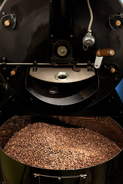 Tuoreet paahdetut luonnolliset kahvipavut, jotka kasaantuvat ulos teollisesta kahvipapujen paahtokoneesta kahvilan sisällä - Valokuva, kuva