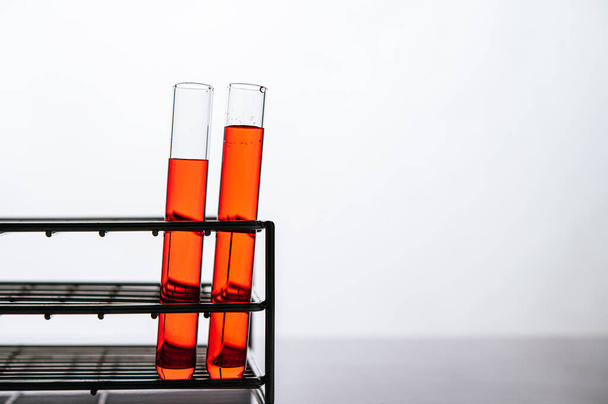 Orangefarbene Chemikalien in einem Wissenschaftsglasrohr, das auf einem Regal steht. - Foto, Bild