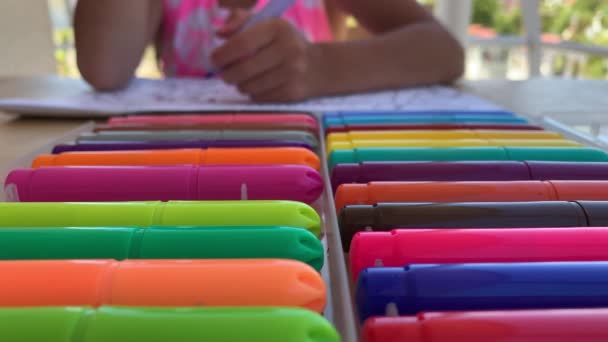 Dítě sedí u stolu a nadšeně kreslí, barvy s barevnými plstěnými pery na papíře, detailní záběr. - Záběry, video