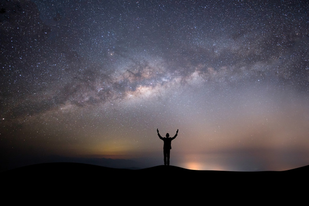 Silhouette erfolgreicher Mann auf der Spitze des Hügels auf einem Hintergrund mit Sternen - Foto, Bild