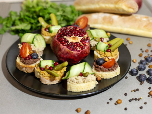 bruschets with pate, cucumbers and tomatoes on a black plate - Foto, imagen