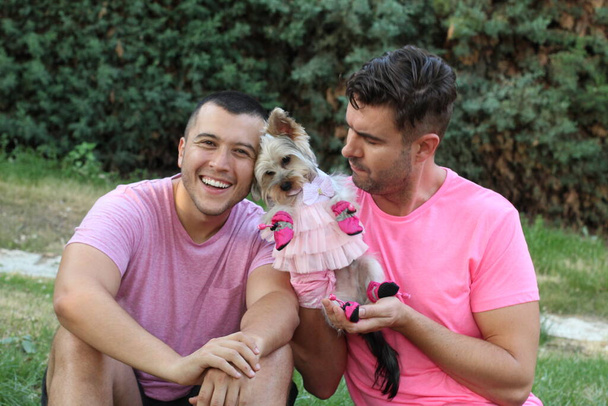 молодая пара геев с милым щенком в платье расслабляющий в парке - Фото, изображение